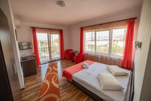 una camera con un letto e due finestre con tende rosse di Pensiunea Zbor a Cluj-Napoca