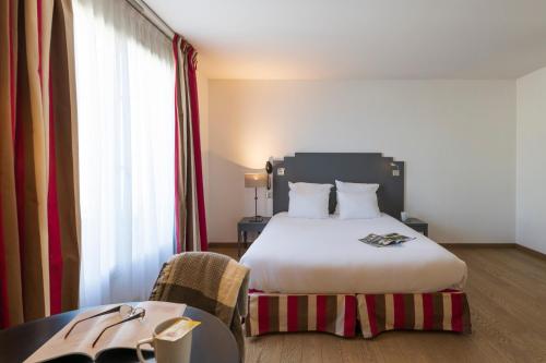 a hotel room with a bed and a table with a table at Hotel Cerise Chatou in Chatou