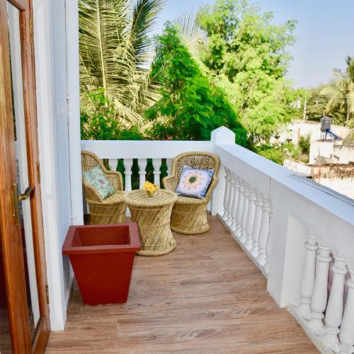a balcony with wicker chairs on a white railing at Jasmin Villa in Hampi