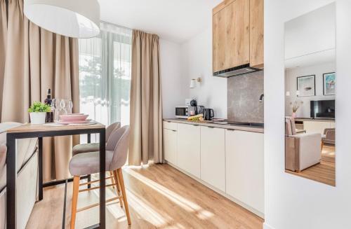 a kitchen with white cabinets and a table with chairs at Jantaris B1 - Apartament 20m od plaży in Mielno