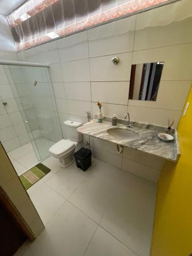 a bathroom with a sink and a toilet and a mirror at Casa na Barra de São Miguel in Barra de São Miguel