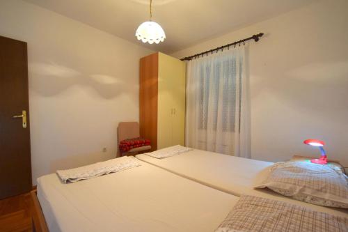 um quarto com uma cama branca e uma janela em Apartments Petrovic em Malinska