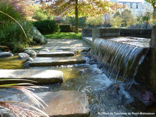a waterfall in a garden with a stone walkway at Hotel Cerise Chatou in Chatou