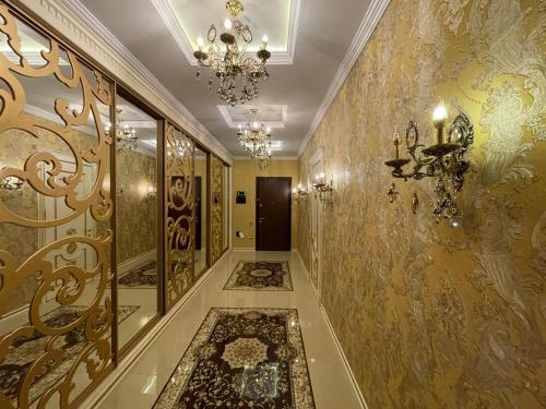 un corridoio con pareti dorate e lampadario pendente di Park Azure Louvre apartment a Baku