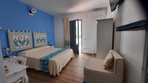 een slaapkamer met blauwe muren en een bed en een stoel bij Hotel Made in Posada