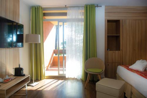 a bedroom with a bed and a window with a balcony at Hôtel Vacances Bleues Delcloy in Saint-Jean-Cap-Ferrat
