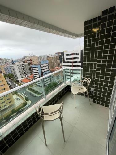 a balcony with two chairs and a view of a city at Apartamento em Jatiúca in Maceió