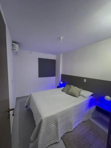 a white bedroom with a bed with a blue light at Apartamento em Jatiúca in Maceió