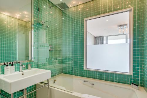 Baño de azulejos verdes con lavabo y espejo en Aqua Views, en Ciudad del Cabo