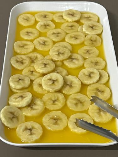 a baking dish filled with bananas in yellow sauce at Guaicurus Hotel in Chapadão do Sul