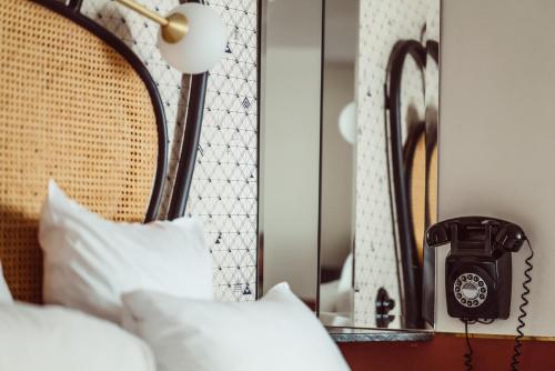 a bedroom with a bed with a phone and a mirror at Hotel Panache in Paris