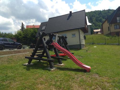 a playground in a yard with a red slide at Babia Chata in Zawoja