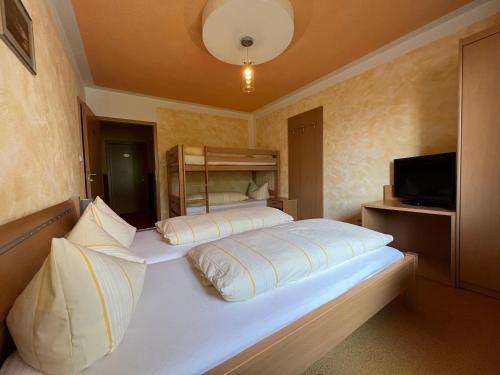 a bedroom with a large white bed and a television at Breitenberger Hof "inklusive Frühstück" in Breitenberg