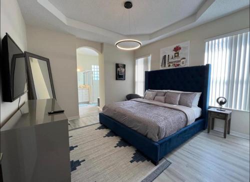 a bedroom with a blue bed and a flat screen tv at Chic villa 4 Bedroom 3 Bath with pool & game room in Davenport