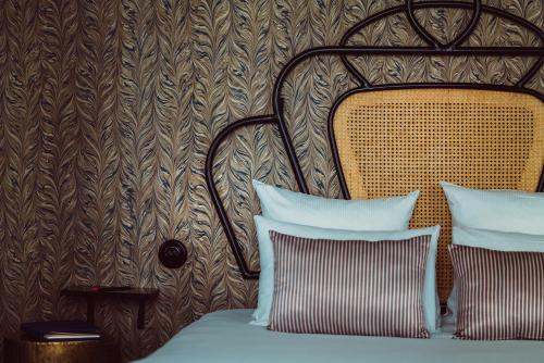 a bed with two pillows in front of a wall at Hotel Panache in Paris