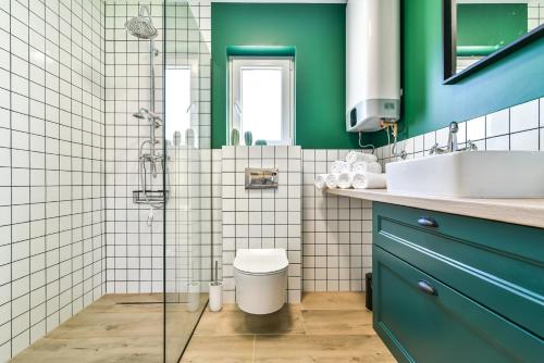 a green bathroom with a toilet and a sink at Domki z Pasją in Kopalino
