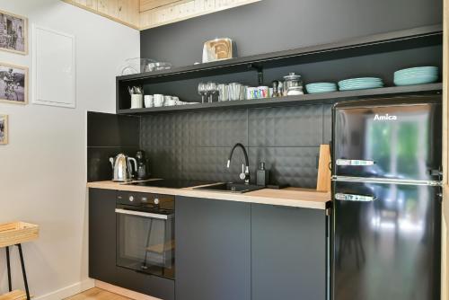 a kitchen with a black refrigerator and a sink at Domki z Pasją in Kopalino