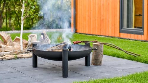 a grill with a fire in a yard at Domki z Pasją in Kopalino