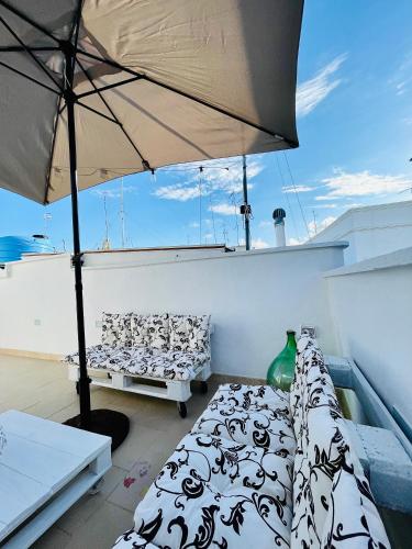 a balcony with two beds and an umbrella on a boat at Casa Perricci - short lets - Monopoli in Monopoli