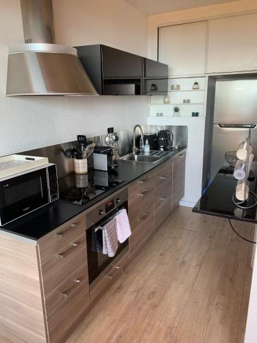 une cuisine avec un micro-ondes et une cuisinière four supérieur dans l'établissement Appartement « Marinella » splendide vue mer aux Sanguinaires, à Ajaccio