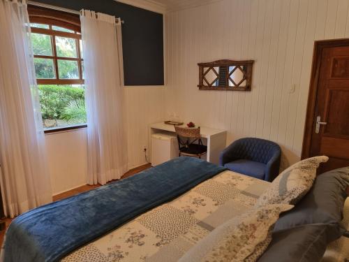 a bedroom with a bed and a chair and a window at Saison Resort & Spa in Itaipava