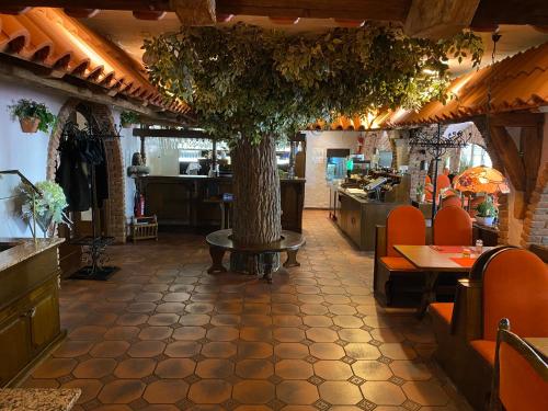 ein Restaurant mit einem Baum in der Mitte eines Zimmers in der Unterkunft Hotel Restaurant Blumenhof in Baesweiler