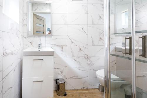 biała łazienka z umywalką i toaletą w obiekcie Zacisze Sosnowe w Łazach