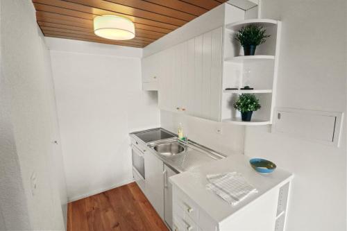 - une cuisine blanche avec des placards blancs et un évier dans l'établissement Superbe appartement avec piscine, à Nendaz