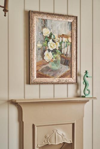 a painting above a fireplace with a vase of flowers at Harold House in Cowes