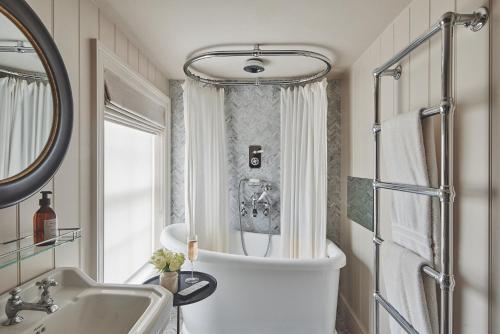 ein Badezimmer mit einer Badewanne, einem Waschbecken und einem Spiegel in der Unterkunft Harold House in Cowes