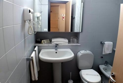 a bathroom with a sink and a toilet and a mirror at Hotel Al Sant'Andrea in Sarzana