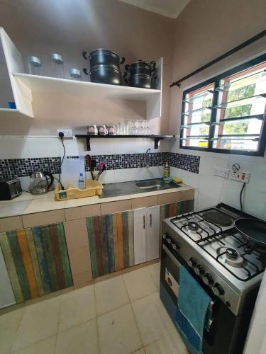 a small kitchen with a stove and a sink at Bedroom Diani Beach in Junda