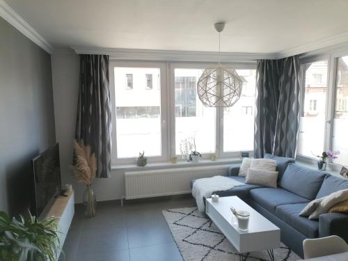 un soggiorno con divano blu e finestre di La casa di Deborah a Namur