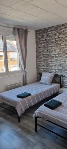 2 camas en un dormitorio con una pared de ladrillo en maison meublée 6 personnes en Cappelle-la-Grande