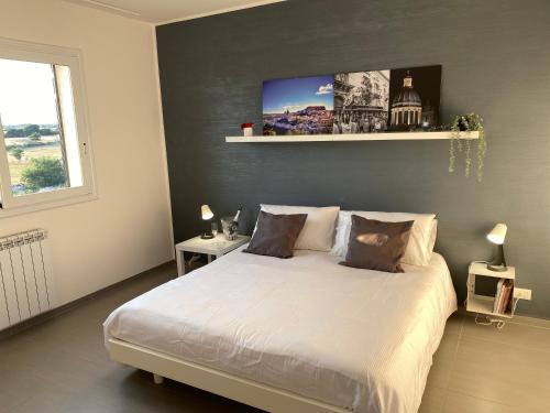 ein Schlafzimmer mit einem weißen Bett mit einem Bild an der Wand in der Unterkunft ROGOS Casa Vacanze in Ragusa