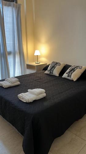 a black bed with two towels on top of it at Departamentos Hipolito Yrigoyen in San Rafael