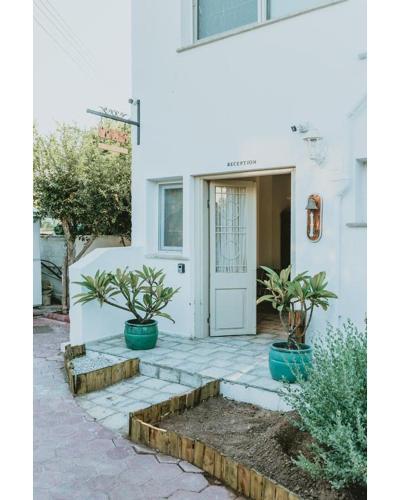 a white house with two potted plants in front of a door at Sunside Inn Hotel in Kérynia