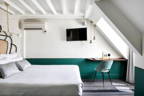 a bedroom with a bed and a desk with a tv at Hotel Panache in Paris