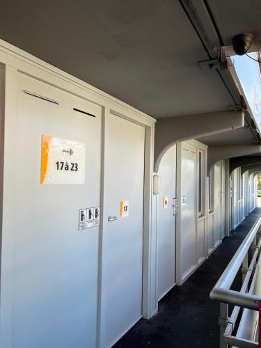 a row of white doors on a building at Premiere Classe Dunkerque Saint Pol Sur Mer in Saint-Pol-sur-Mer