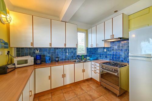 a kitchen with white cabinets and a blue tiled wall at Caribbean Sea View Holiday Apartments in Méro