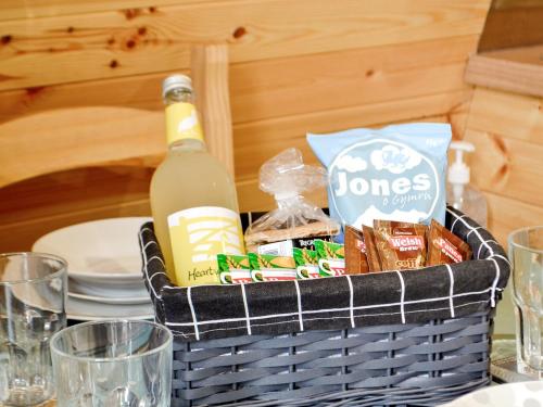 a picnic basket with a bottle of wine and snacks at Castle View Glamping in Llanbister