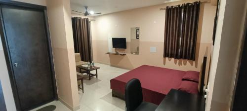 a bedroom with a red bed and a room with a television at Mi Casa Sector 47 in Gurgaon