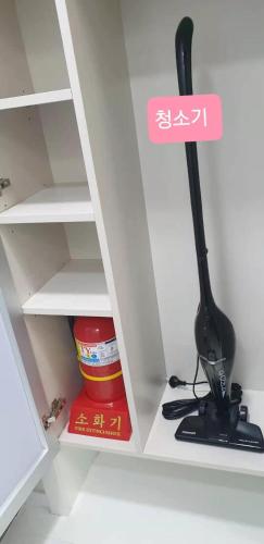 a black object in a white cabinet with a broom at Shine Hotel Incheon Airport in Incheon