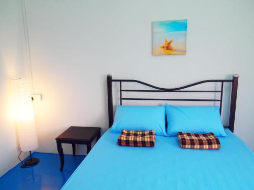 a bedroom with a blue bed with two pillows at The Cardamom Hostel in Melaka