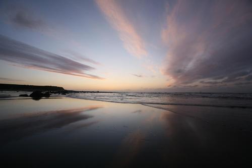 a sunset on a beach with the ocean at Ahu Ahu Beach Villas in Oakura