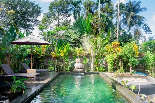 a swimming pool in a garden with an umbrella at Sandora Homestay with Private Pool by Supala in Ubud
