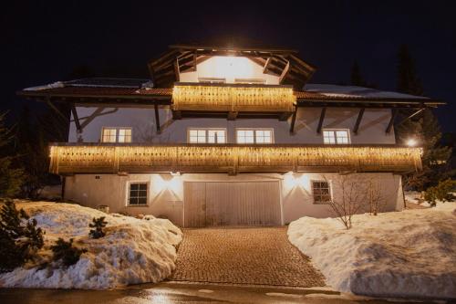 una casa iluminada con mucha nieve en Hirsch-Lounge, en Höchenschwand