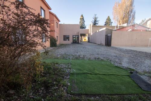 eine Auffahrt eines Hauses mit einem Garten voller Gras in der Unterkunft 349 Suites in El Calafate