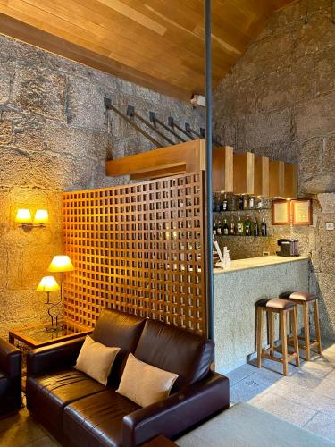 a living room with a leather couch and a bar at Hotel de Charme Quinta do Pinheiro in Freamunde