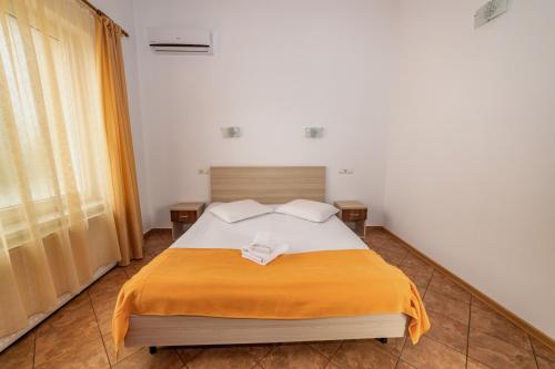 a bedroom with a bed with a orange blanket at Pensiunea Zbor in Cluj-Napoca